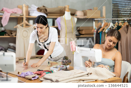 Two female tailors working on custom garment in studio Two female tailors working on custom garment in studio 136644521