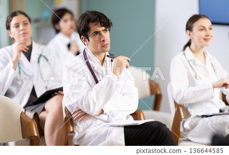 Young female doctor listening and taking notes in lecture hall Young female doctor listening and taking notes in lecture hall 136644585