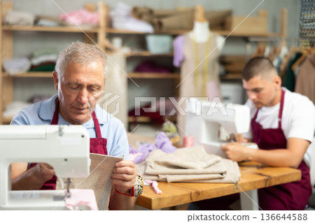Two male tailors working with fabric Two male tailors working with fabric 136644588