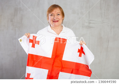 Smiling elderly woman waving national Georgian flag 136644590