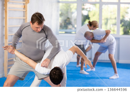 Guy and man are training in gym practicing hand grab technique Guy and man are training in gym practicing hand grab technique 136644596