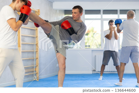 Two men training boxing and kicking in studio Two men training boxing and kicking in studio 136644600