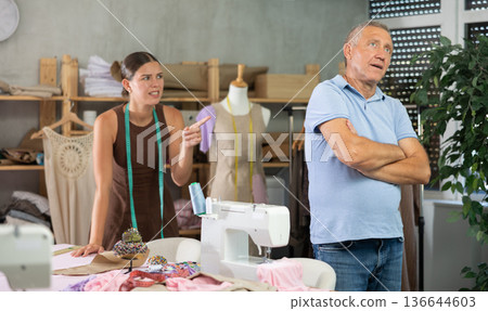 Girl head of sewing workshop yells at her subordinate mature man seamstress Girl head of sewing workshop yells at her subordinate mature man seamstress 136644603