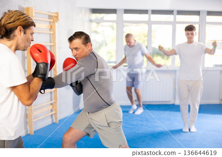 Men in boxing gloves punch deliver blow each other during training sparring session. 136644619
