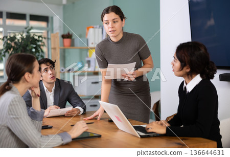 woman discusses the project with a team at a table 136644631