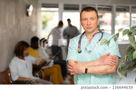 Serious professional doctor in turquoise scrub standing in lobby of clinic 136644639