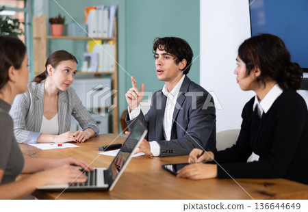 Man talks to young colleagues in the office Man talks to young colleagues in the office 136644649