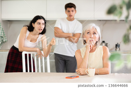 Adult children guy and girl are fighting with elderly woman mother. Adult children guy and girl are fighting with elderly woman mother. 136644666