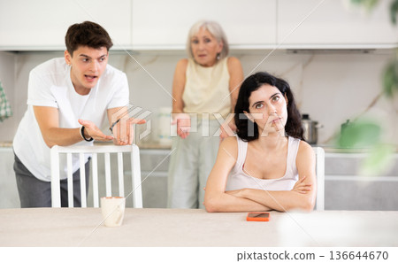 Elderly woman mother and young guy during family quarrel accuse adult daughter Elderly woman mother and young guy during family quarrel accuse adult daughter 136644670