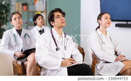 Young female doctor listening and taking notes in lecture hall 136644753