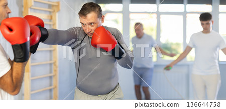 Men in boxing gloves punch deliver blow each other during training sparring session. Men in boxing gloves punch deliver blow each other during training sparring session. 136644758