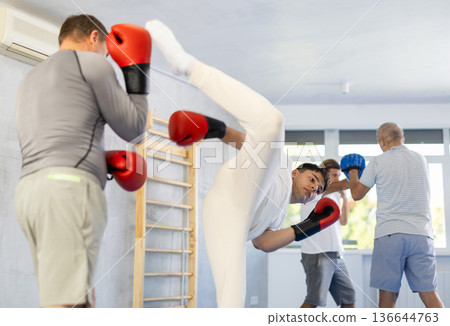 Man with young guy sparring during kickboxing training and practicing kicks Man with young guy sparring during kickboxing training and practicing kicks 136644763
