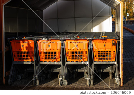 Urban retail setting with carts and shadows. Empty shopping carts lining quiet city market area Urban retail setting with carts and shadows. Empty shopping carts lining quiet city market area 136646069