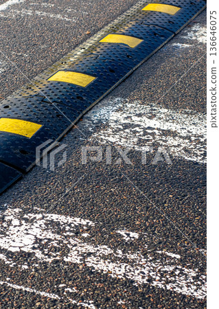 Colorful raised obstacle on worn roadway emphasizes safety and attentive driving in city conditions 136646075