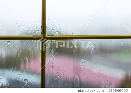 Rainy window scene. Gloomy window capturing blurred roof and subdued lighting atmosphere Rainy window scene. Gloomy window capturing blurred roof and subdued lighting atmosphere 136646093
