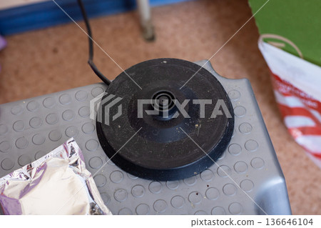 Cozy kitchen space featuring small electric kettle resting on textured rubber surface Cozy kitchen space featuring small electric kettle resting on textured rubber surface 136646104