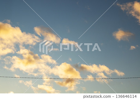 Calm sunset with drifting clouds. Serene blue sky with illuminated clouds and open landscape Calm sunset with drifting clouds. Serene blue sky with illuminated clouds and open landscape 136646114