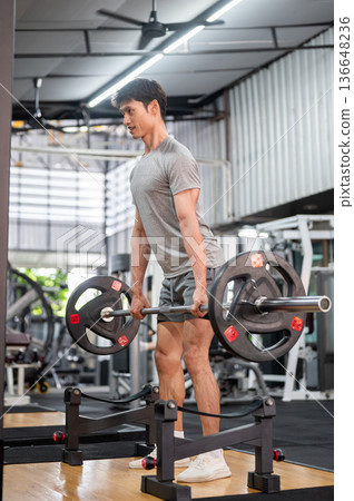 Strong asian man client in sportswear standing holding barbell exercising doing weight lift in gym. Strong asian man client in sportswear standing holding barbell exercising doing weight lift in gym. 136648236