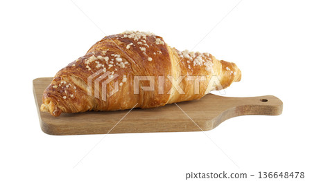 Golden brown croissant with sugar crystals on a rustic wooden cutting board 136648478
