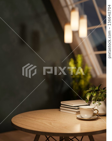 Coffee cup and books on round wooden table with hanging lamp under roof window in dim lit attic room Coffee cup and books on round wooden table with hanging lamp under roof window in dim lit attic room 136648704