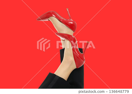 A woman shows off red high heels with legs raised A woman shows off red high heels with legs raised 136648779
