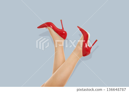 Bright red high heel shoes are presented with legs crossed 136648787
