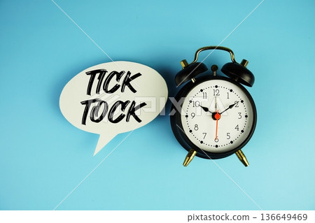 Tick Tock text on speech bubble with alarm clock on blue background Tick Tock text on speech bubble with alarm clock on blue background 136649469