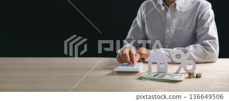 Person calculates property mortgage interest rate, diligently managing home loan finance using calculator, dollar bills and coins represent investment percentage analysis for future planning Person calculates property mortgage interest rate, diligently managing home loan finance using calculator, dollar bills and coins represent investment percentage analysis for future planning 136649506