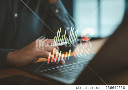 Person Using Laptop with Data Analytics Graphs and Charts Overlay 136649538