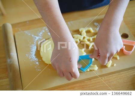 Close-up of a child cutting dough with a cookie cutter and making a cookie Close-up of a child cutting dough with a cookie cutter and making a cookie 136649662