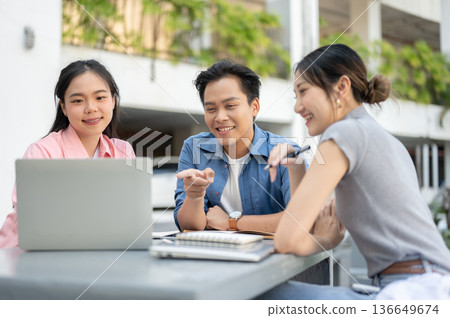 Man woman asian student friends looking at laptop aside books working on group project at university Man woman asian student friends looking at laptop aside books working on group project at university 136649674