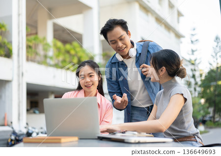 Asian man student explaining and helping woman friend on assignment in laptop at table in university Asian man student explaining and helping woman friend on assignment in laptop at table in university 136649693