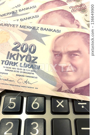 Turkish Lira and Calculator Finance Concept. 200 TRY banknotes on calculator representing Turkish economy, budgeting, and financial planning. 200 Turkish Lira banknotes placed on a black calculator. Turkish Lira and Calculator Finance Concept. 200 TRY banknotes on calculator representing Turkish economy, budgeting, and financial planning. 200 Turkish Lira banknotes placed on a black calculator. 136649900
