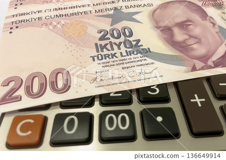 Turkish Lira and Calculator Finance Concept. 200 TRY banknotes on calculator representing Turkish economy, budgeting, and financial planning. 200 Turkish Lira banknotes placed on a black calculator.  136649914