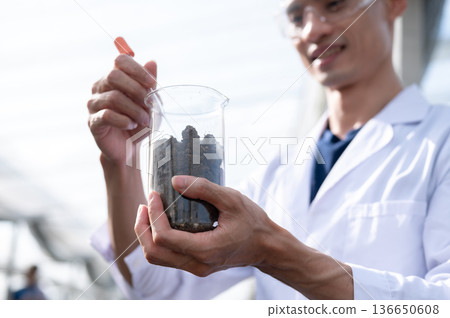 Glasses asian agricultural scientist man holding beaker testing planting soils in a greenhouse farm Glasses asian agricultural scientist man holding beaker testing planting soils in a greenhouse farm 136650608