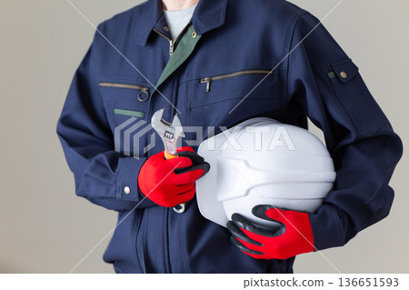 Middle-aged male businessman in work clothes holding tools and a helmet 136651593