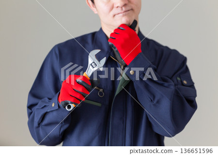 一位身穿工作服的中年男性商人,手持工具,神情憂慮。 一位身穿工作服的中年男性商人,手持工具,神情憂慮。 136651596