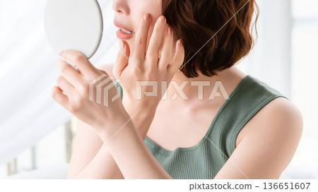 Woman checking her skin in the mirror - beauty image Woman checking her skin in the mirror - beauty image 136651607