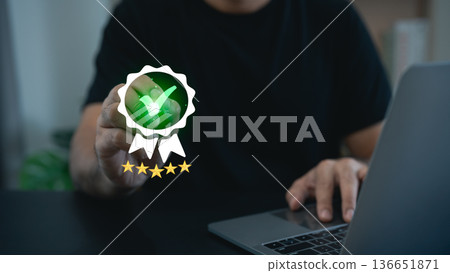 Person Holding a Green Check Mark Badge Symbolizing Achievement with Laptop on Table in Modern Office Setting Person Holding a Green Check Mark Badge Symbolizing Achievement with Laptop on Table in Modern Office Setting 136651871