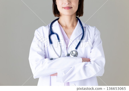 A middle-aged female nurse in a white coat with her arms folded A middle-aged female nurse in a white coat with her arms folded 136653065