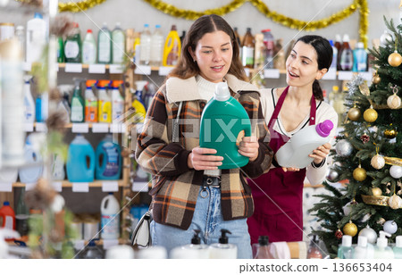 Girl consultant helps female buyer choose laundry softener Girl consultant helps female buyer choose laundry softener 136653404