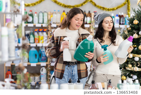 Young girls choosing cleaning spray and detergent in store with New Year decoration Young girls choosing cleaning spray and detergent in store with New Year decoration 136653408