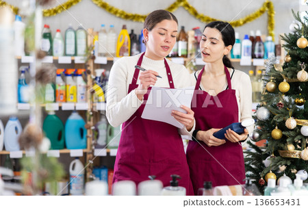 Two saleswomen fill out documents against the background of a Christmas tree 136653431