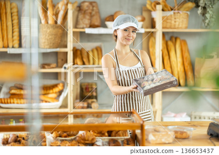 Girl entrepreneur owner of bakery holds out box with cookies in hand 136653437
