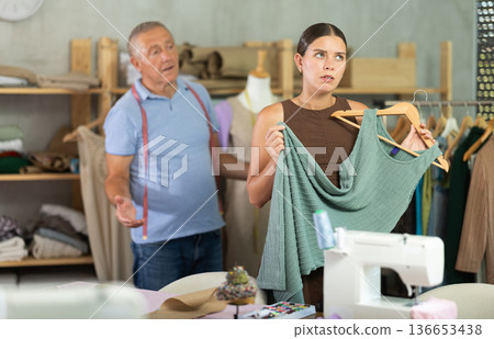 Senior man tailor apologizes to angry girl client. Senior man tailor apologizes to angry girl client. 136653438