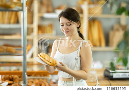 Portrait of a young girl with a bocadillo in her hands in the interior of private bakery Portrait of a young girl with a bocadillo in her hands in the interior of private bakery 136653595