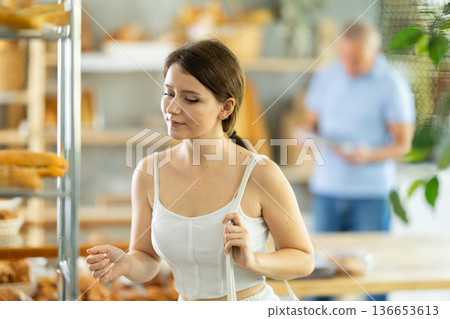Girl choosing fresh baked goods on display in private bakery Girl choosing fresh baked goods on display in private bakery 136653613