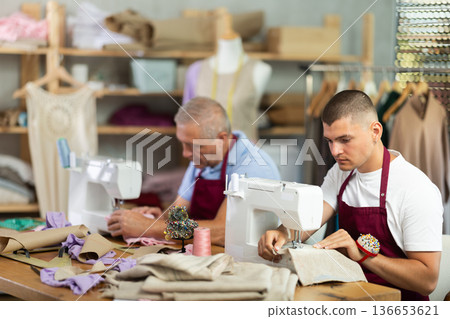 Two male workers in the atelier sewing Two male workers in the atelier sewing 136653621