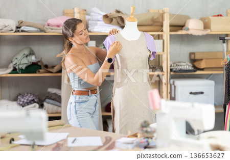 dressmaker stands near the mannequin in the workshop 136653627