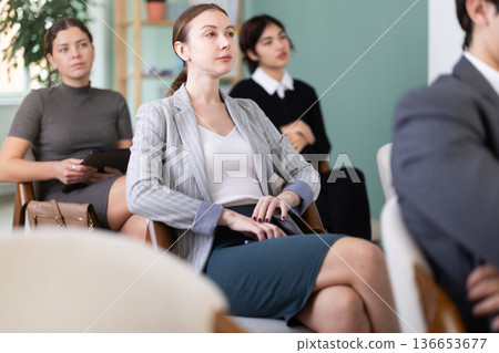 Young woman listens to presentation in conference room 136653677